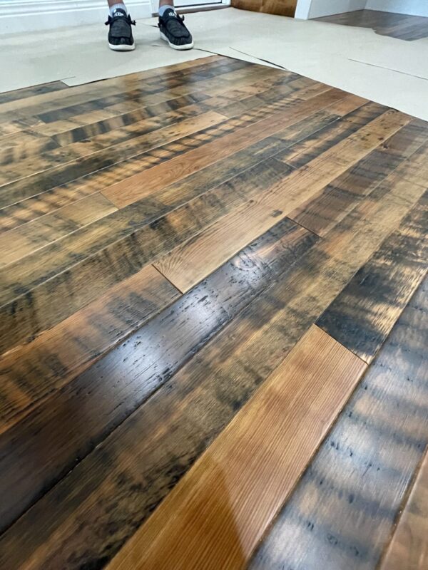 A person standing on a wooden floor in a kitchen.