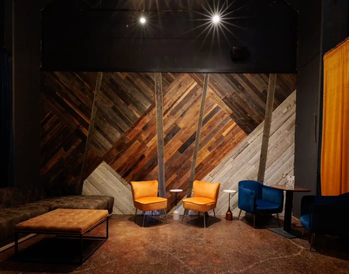 A room with a wooden wall and orange chairs.