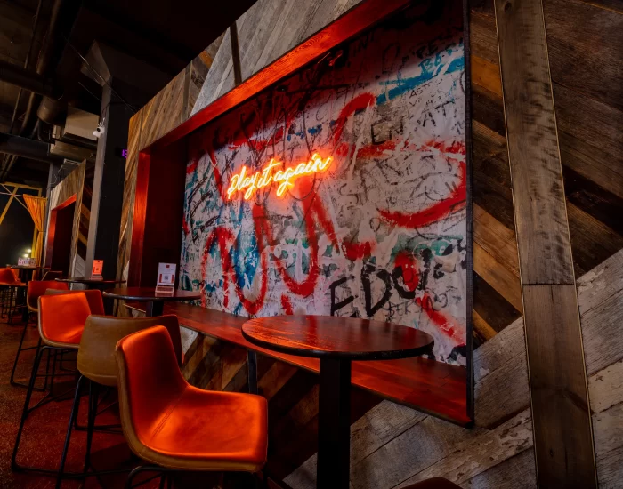 A bar with red chairs and graffiti on the wall.