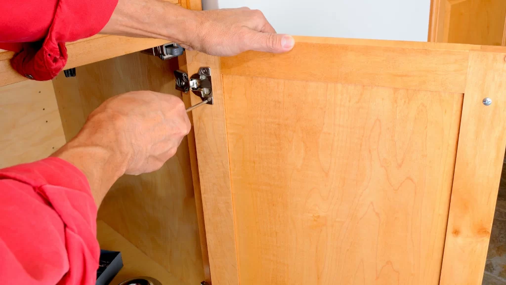 A man removing cabinet hinges