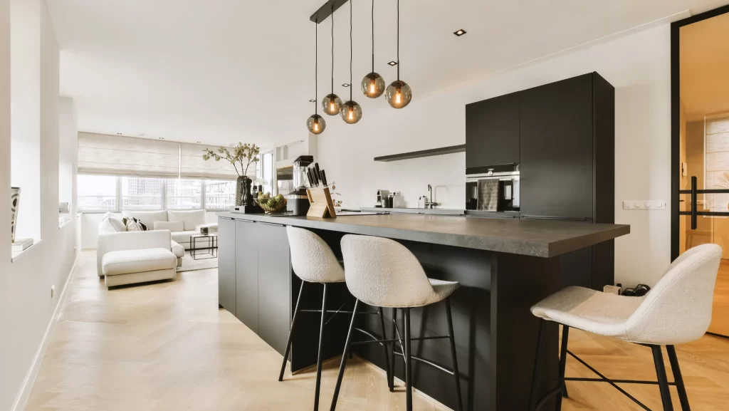 a kitchen and dinning area in a modern apartment with white walls, hardwood flooring and black cabinetry on the island