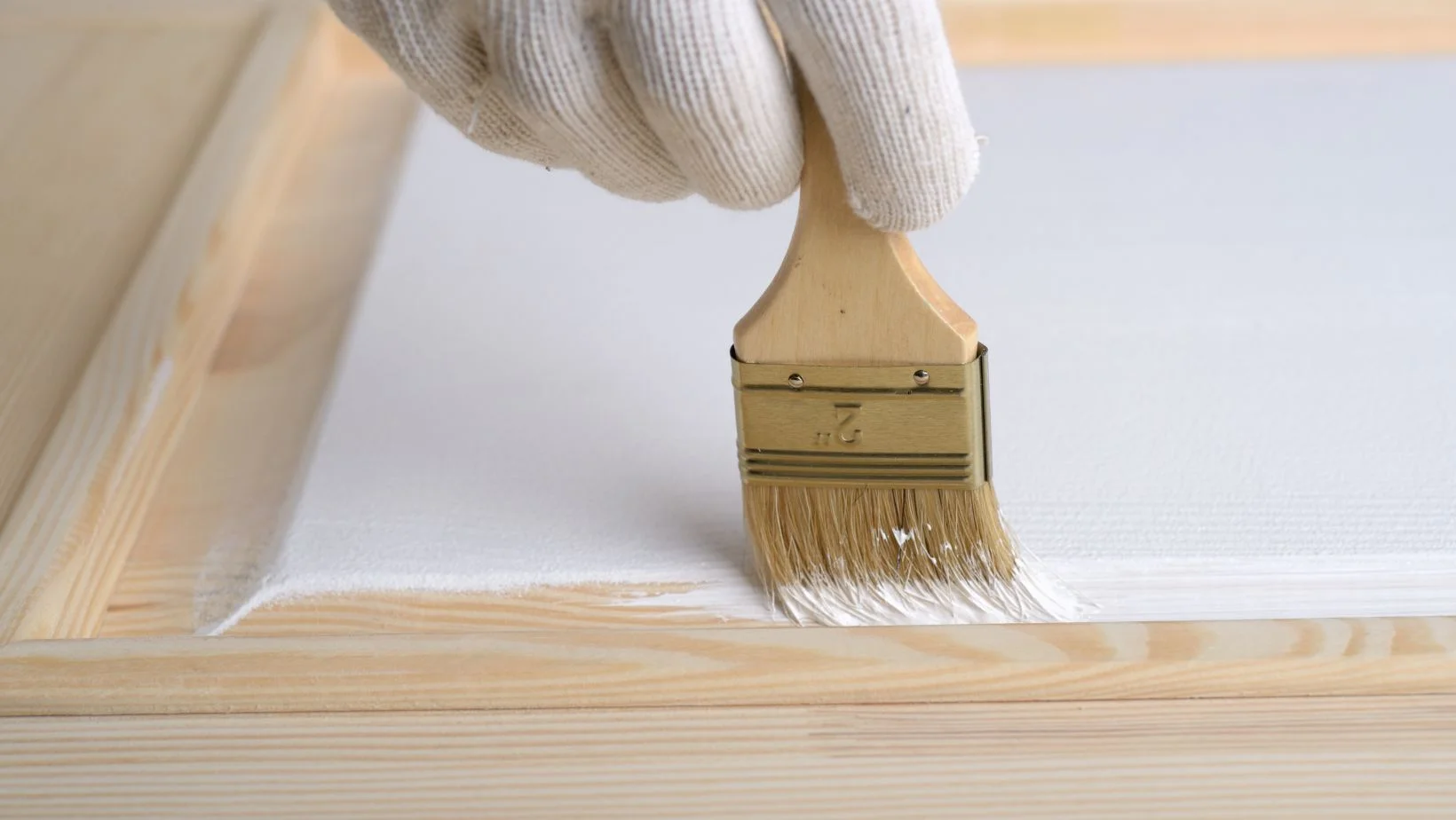 A person painting a door white with a painting brush