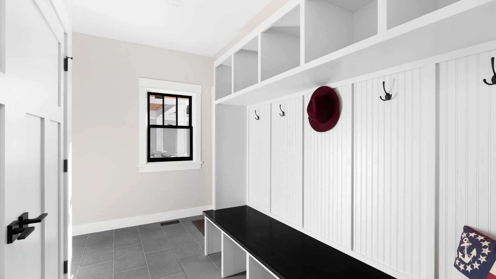 A white farmhouse mud room with a bench seat and coat hooks.