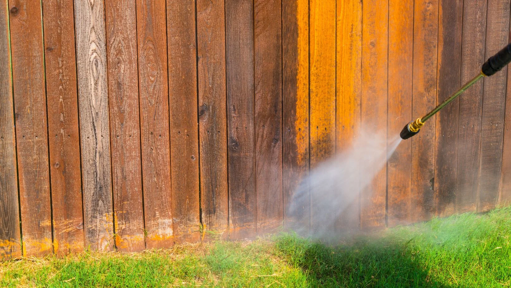 cleaning a wooden fence with a hose